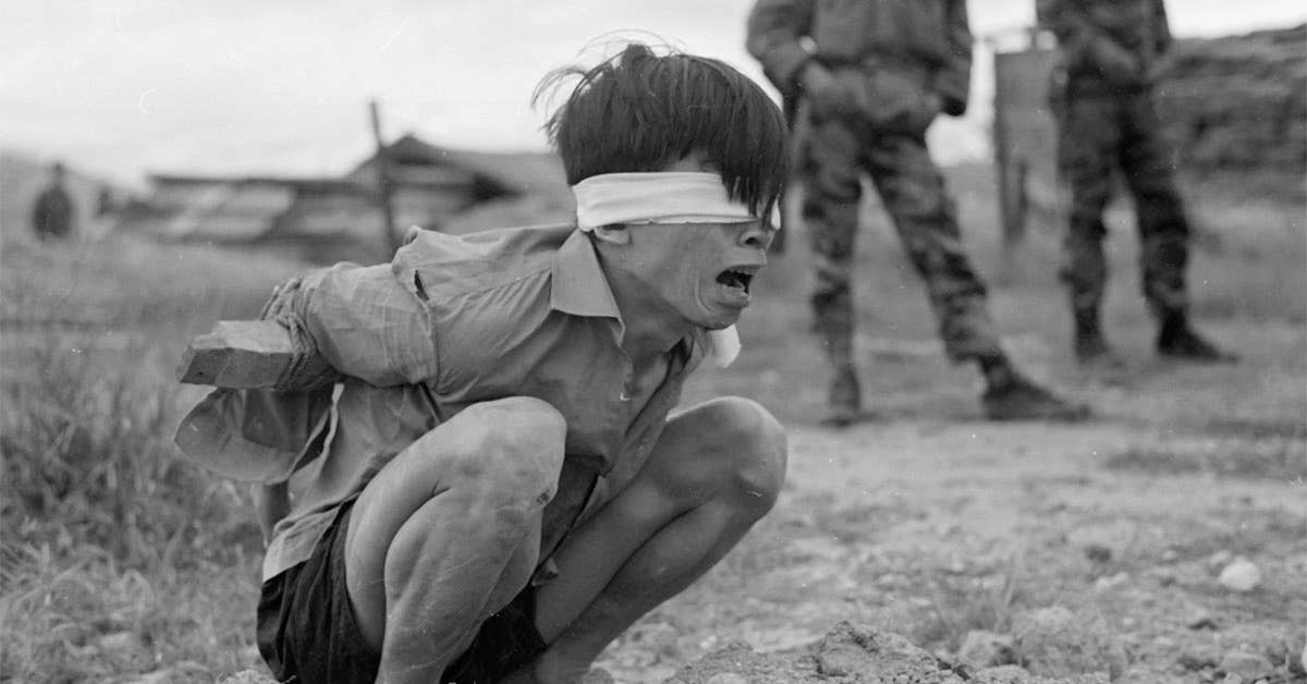 A Viet Cong prisoner is interrogated at the A-109 Special Forces Detachment in Thuong Duc, 25 km west of Da Nang, 1967. Photo under Public Domain,