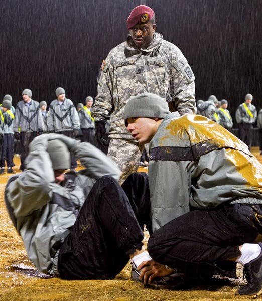 Sgt. 1st Class Eric Lloyd, grades the sit-up event of an Army Physical Fitness Test during early-morning rain at Fort Bragg, N.C.<br> 