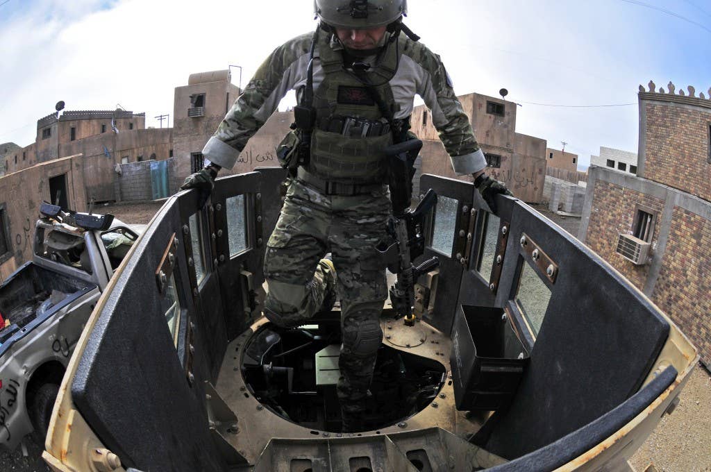 A Navy special warfare specialist assigned to Seal Team 7, a unit comprised of both active and reserve component members based in Coronado, Calif., climbs into the turret gunner position during a mobility training exercise through a simulated city. SEAL Team 7 is conducting a pre-deployment work-up cycle.