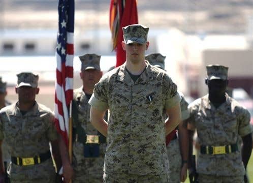 Lance Cpl. Brady Gustafson, a machine gunner with Golf Company, 2nd Battalion, 7th Marine Regiment, stands in from of the battalion at perfect parade rest, despite the amputation of his right leg below the knee. Gustafson received the Navy Cross and a meritorious promotion to corporal during a ceremony March 27 at Lance Cpl. Torrey Grey Field. Photo: Pfc. Michael T. Gams/USMC