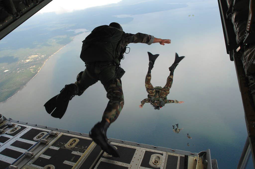 Members of the Air Force's 720th Special Tactics Group jump out of an airplane wearing flippers.