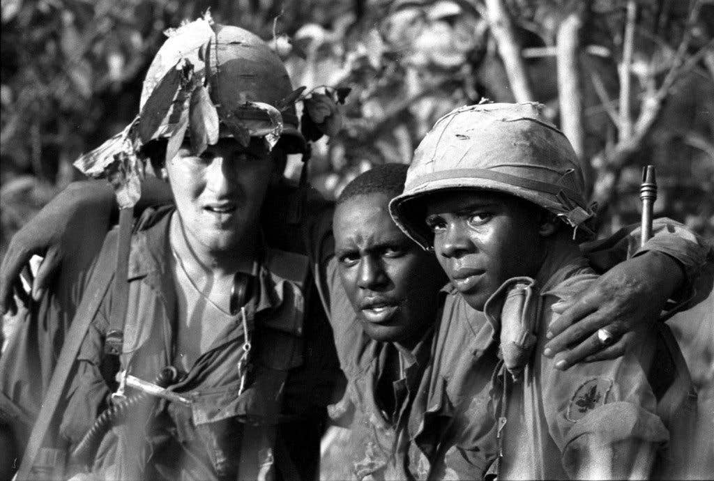 A wounded soldier is helped to a waiting helicopter by two of his comrades  near Near Tay Ninh, South Vietnam,  November 1966 (Stars Stripes)