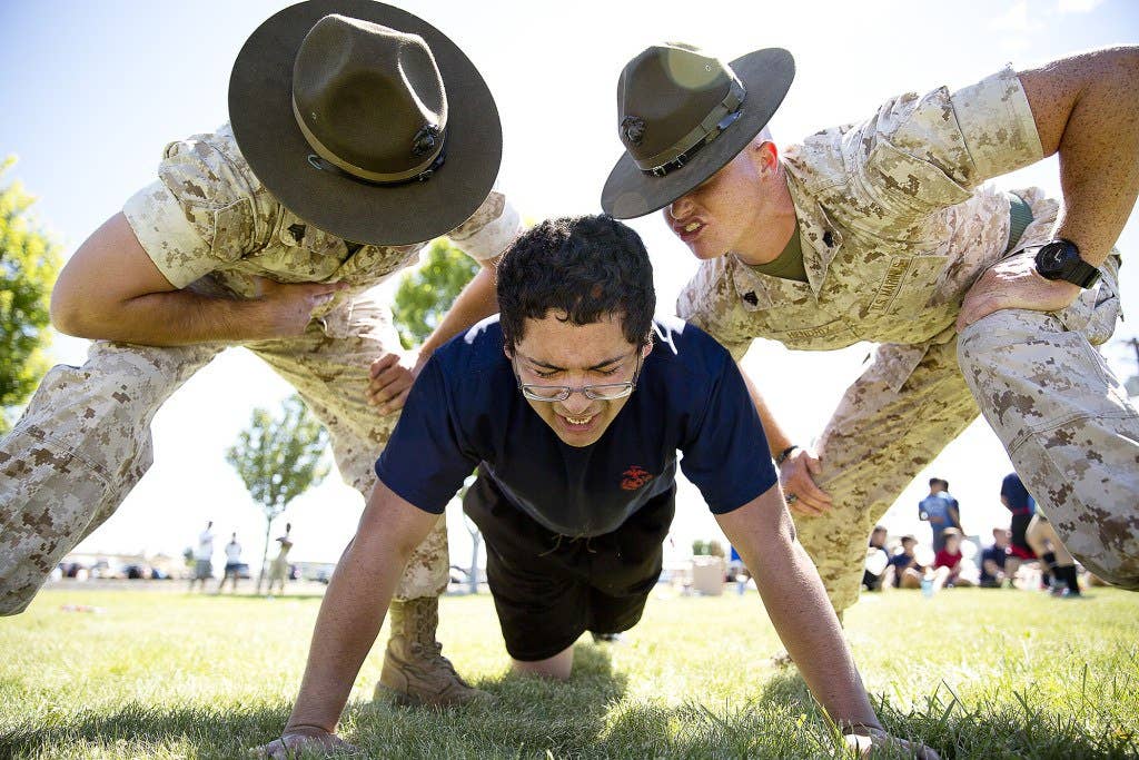 Sgts. Stephen Wills (left) and Brandon Hendrix, drill instructors from Marine Corps Recruit Depot San Diego, motivate Jose Garcia, a Marine enlistee from Yakima, Wash., during a Recruiting Station Seattle pool function at the Yakima Training Center in Yakima, July 17, 2015. During the event, recruiters teamed with drill instructors to physically and mentally prepare enlistees from Washington and Idaho for boot camp. The enlistees, part of the Marine Corps delayed entry program, are awaiting their ship dates. Wills, 24, is from Phoenix and is assigned to Echo Company, 2nd Recruit Training Battalion. Hendrix, 26, is from Redlands, Calif., and is assigned to Lima Company, 3rd Recruit Training Battalion. Garcia, 17, is set to become a senior at Eisenhower High School in Yakima and was recruited by Sgt. James Campos. (U.S Marine Corps photo by Sgt. Reece Lodder)
