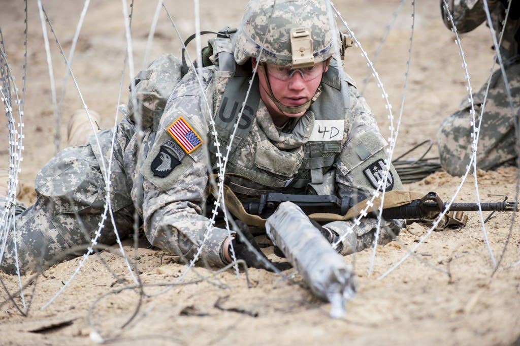 Spc. Ryan Rolf, a combat engineer from Fullerton, Nebraska, with the 402nd Engineer Company, places a field expedient bangalore packed with C-4 explosive in a barbed wire obstacle during an in-stride breach event at the 2014 Sapper Stakes competition at Fort McCoy, Wis., May 5. (U.S. Army photo by Sgt. 1st Class Michel Sauret)