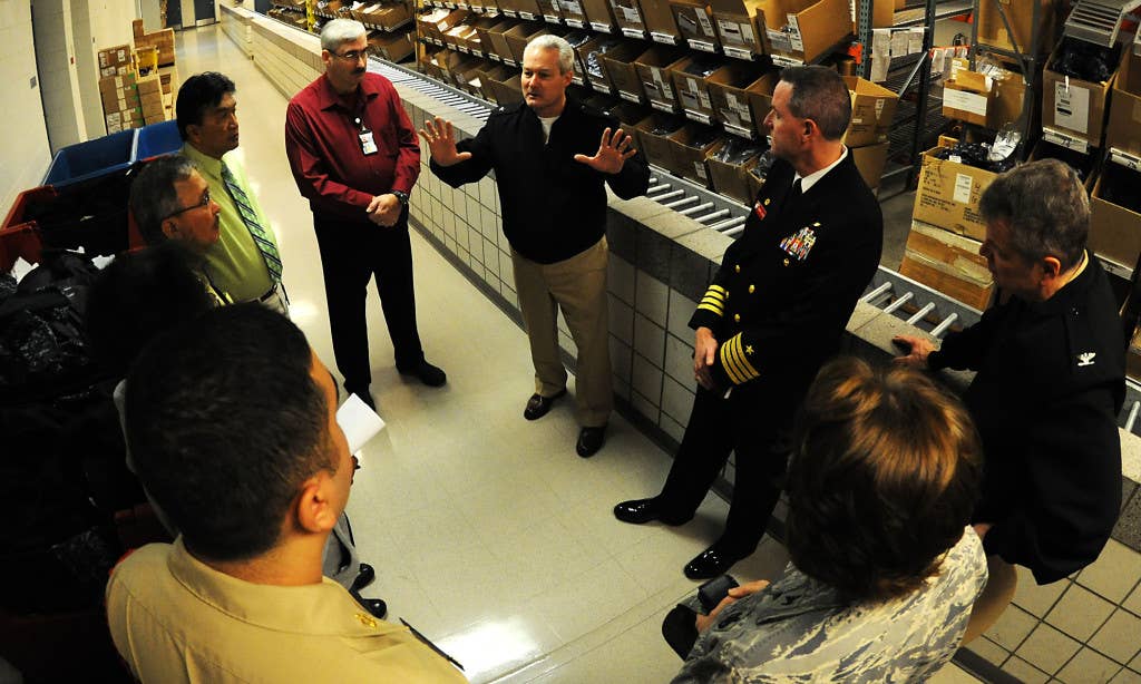 Rear. Adm. David Baucom, seen here wearing clothes, tours a uniform issue facility that is full of clothes. Photo: US Navy Mass Communications Specialist 1st Class Andre N. McIntyre