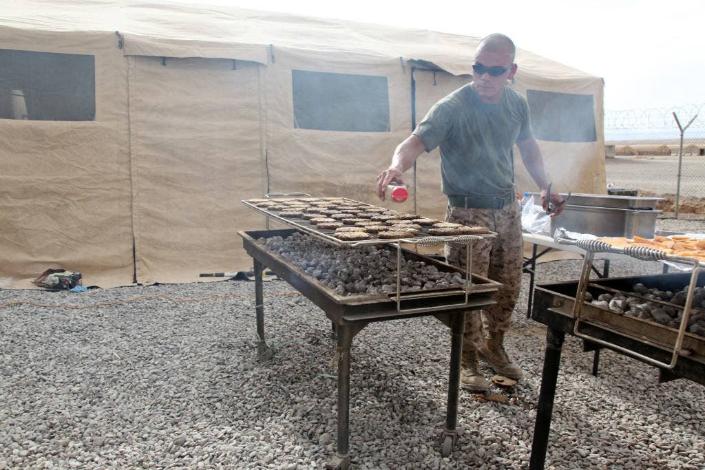 U.S. Marine Corps Sgt. Mark A. Santos, a food service specialist with Headquarters Company, Regimental Combat Team 6, adds seasoning to the hamburger patties for the evening meal outside the new Dining Facility (DFAC) on Camp Delaram II, Nimroz province, Afghanistan June 16, 2012. The DFAC was converted from a former water treatment facility as part of the ongoing process to consolidate and demilitarize the camp. (U.S. Marine Corps photo)