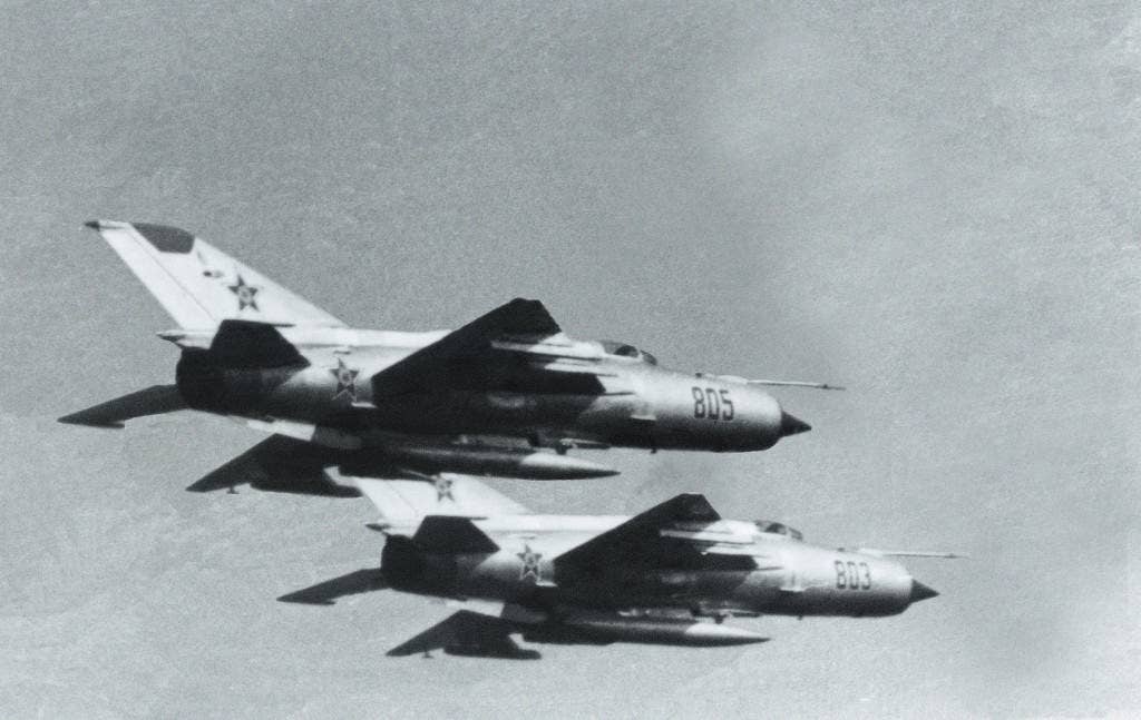 A right underside view of two Soviet MiG-21 Fishbed fighter aircraft in flight.
