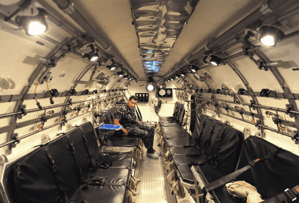 A U.S. Navy sailor sits in one of the Navy's two 32-seat submarine Decompression Systems. Photo: US Navy Mass Communication Specialist 2nd Class Kyle Carlstrom