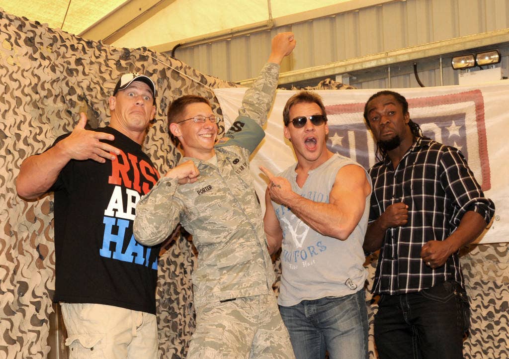 Airman 1st Class Logan Porter strikes a pose with World Wrestling Entertainment superstars John Cena, Chris Jericho and Kofi Kingston during a USO visit Feb. 10, 2012. The wrestlers took photos and signed autographs with more than 200 airmen and soldiers assigned to the 380th Air Expeditionary Wing.