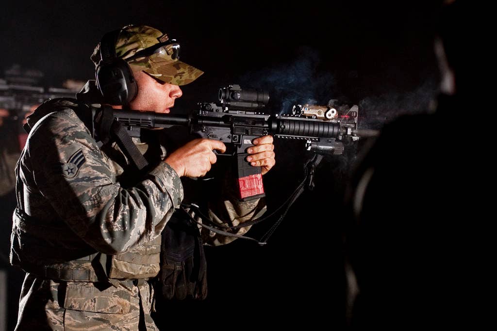 Senior Airman Cody Fuller, a 122nd Security Forces member from the 122nd Fighter Wing in Fort Wayne, Ind., aims his PEQ-15 laser device on the target, while smoke from burst firing his M4 carbine fills the air, April 11, 2015, at Fort Custer, Michigan. Airmen train in both day and low light conditions to qualify during the course of fire. (U.S. Air National Guard photo by Staff Sgt. William Hopper)