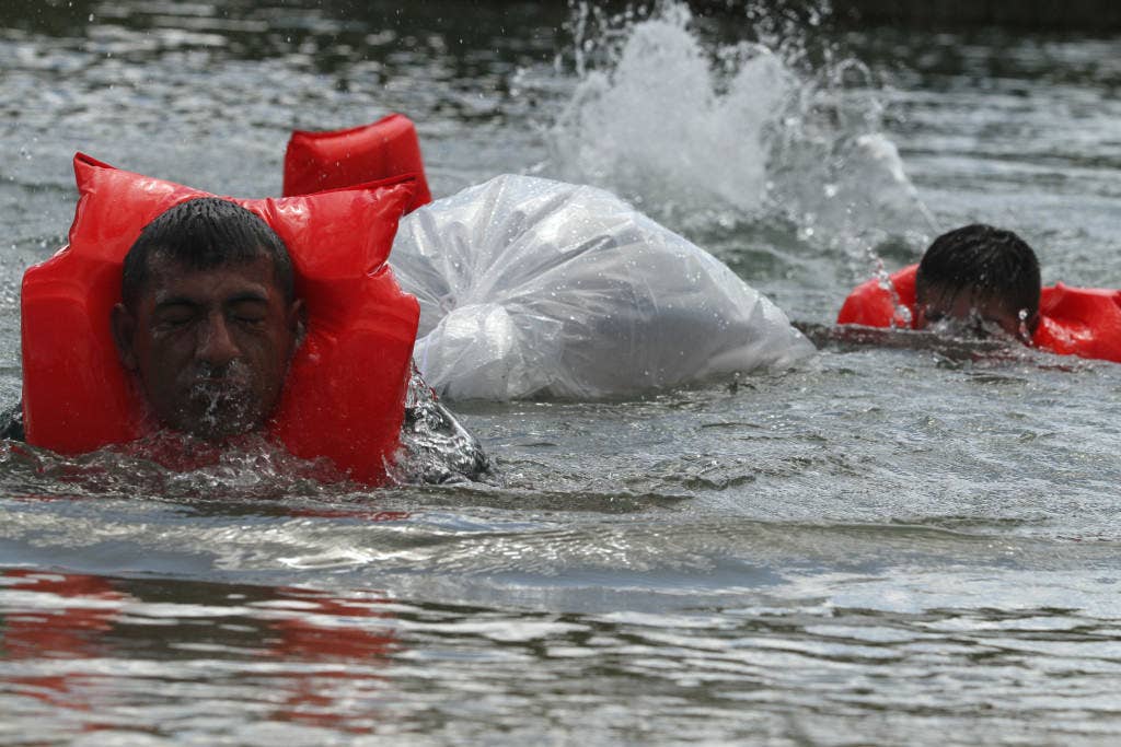 Peruvian team members swim down a creek while pulling their gear during last year's Fuerzas Comando. (U.S. Army photo by Sgt. Andrew Kuhn)