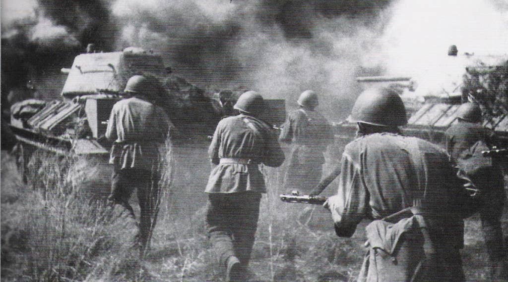 Soviet soldiers advance behind a T-34 tank through thick smoke. (Photo: public domain)