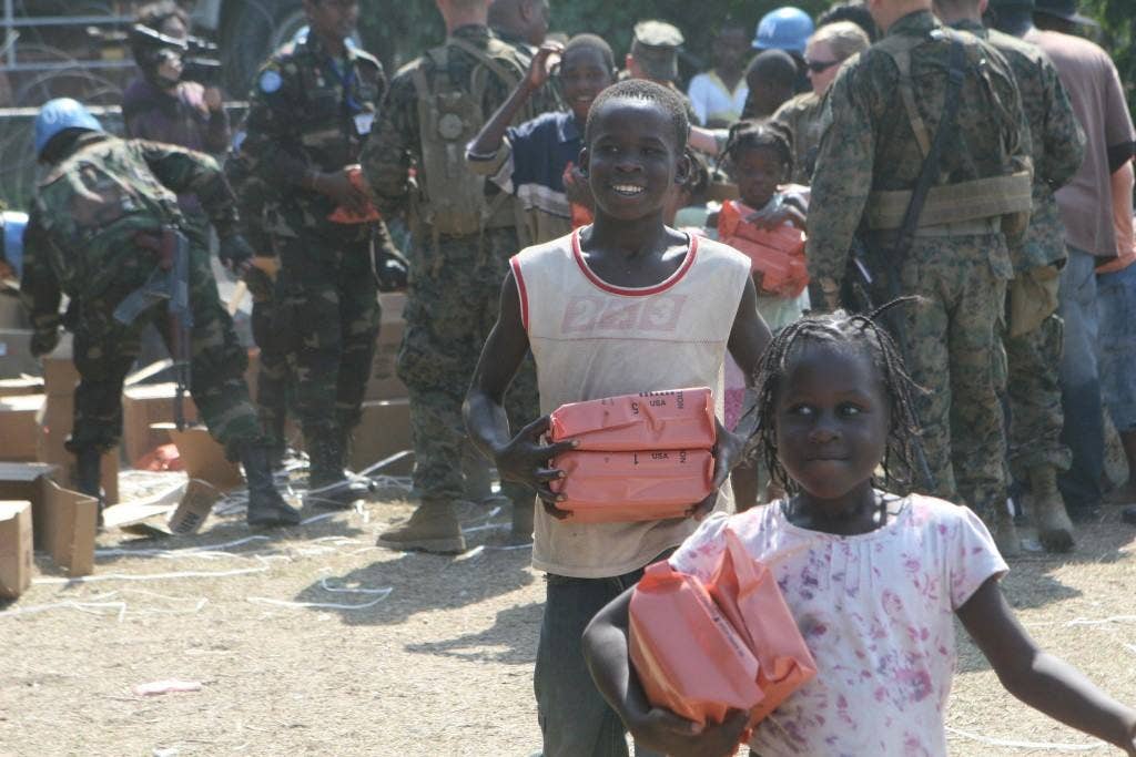 Two Haitian children run back to their families after receiving packages of MREs, while Marines and Sri Lankan United Nations forces hand out food to Haitians Jan. 24, 2010 as part of recovery efforts following a 7.0 earthquake. (U.S. Marine Corps photo by Cpl. Michele Watson)