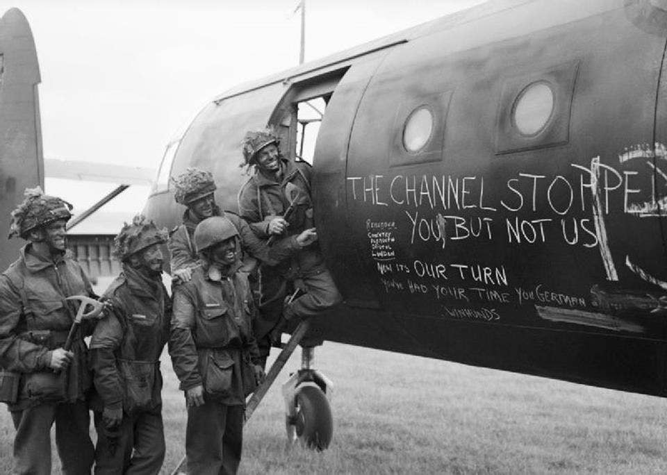 Airborne troops admire the graffiti chalked on the side of their glider as they prepare to fly out as part of the second drop on Normandy on the night of 6th June 1944. Airborne troops of 6th Airlanding Brigade admire the graffiti chalked on the side of their Horsa glider at an RAF airfield as they prepare to fly out to Normandy as part of 6th Airborne Division's second lift on the evening of 6 June 1944. Image by War Office official photographer, Malindine E G (Capt).