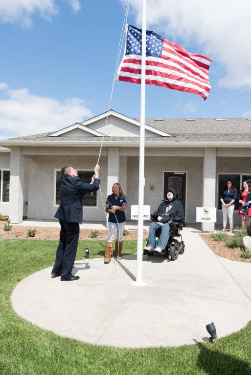 HOFT Executive Director, Bill Ivy raising a flag outside Sgt. Mendes' new home.