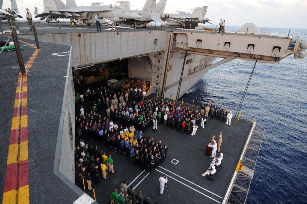 Sailors assigned to the aircraft carrier USS Ronald Reagan and Carrier Air Wing 14, assemble on an aircraft elevator for a wreath-laying ceremony in remembrance of the sailors who fought and died at the Battle of Midway. Midway is a great moment in US Navy history and is considered by many to be the turning point in the battle of the Pacific during World War II. | US Navy photo by Mass Communication Specialist 2nd Class Joseph M. Buliavac