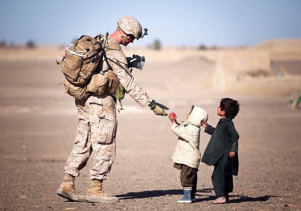 Lance Cpl. Tom Morton, a team leader with Kilo Company, 3rd Battalion, 3rd Marine Regiment hands an Afghan child a toy during a security patrol in Garmsir District, Helmand province, Afghanistan, Feb. 25, 2012. (U.S. Marine Corps photo by Cpl. Reece Lodder)