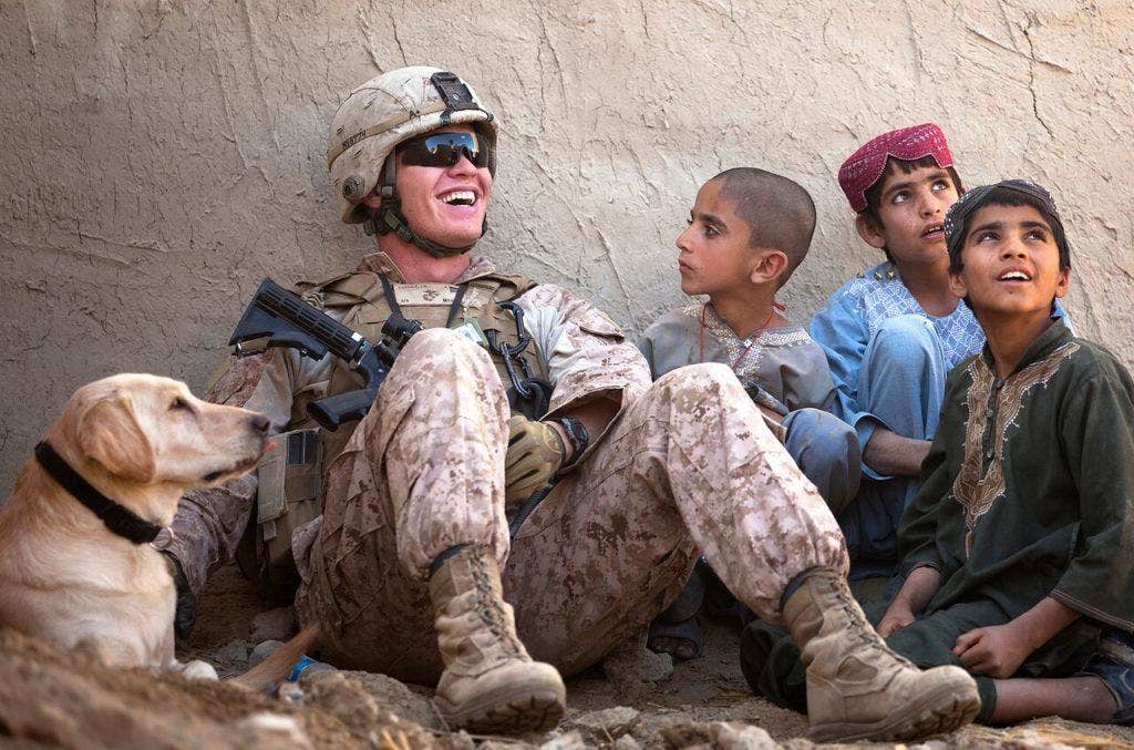 Lance Cpl. Isaiah Schult, a dog handler with Jump Platoon, Headquarters and Service Company, 3rd Battalion, 3rd Marine Regiment, and 20-year-old Indianapolis native, jokes with Afghan children while providing security with Big, an improvised explosive device detection dog, during a shura outside a local residence in Garmsir District, Helmand province, Afghanistan, Nov. 22, 2011. (U.S. Marine Corps photo by Cpl. Reece Lodder)