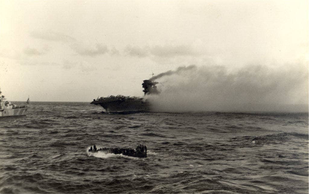 Crewmen abandon ship on board the U.S. aircraft carrier USS Lexington (CV-2) after the carrier was hit by Japanese torpedoes and bombs during the Battle of the Coral Sea, on 8 May 1942. (Photo: U.S. Navy National Museum of Naval Aviation)