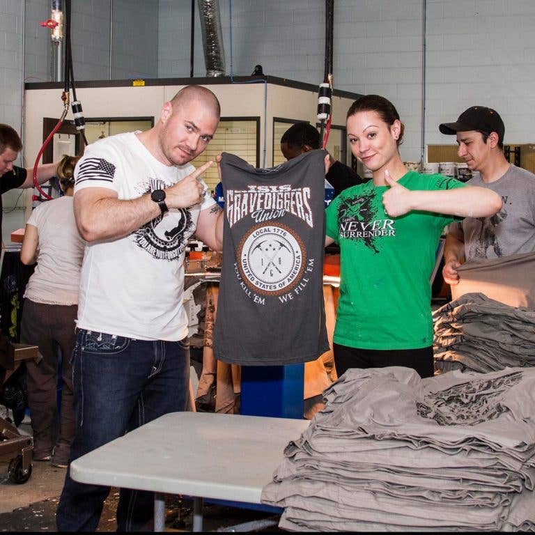 Alarik on the Grunt Style factory floor with an employee holding up the 1,000,000 t-shirt the company has manufactured. The company has since surpassed the 2,000,000 mark. (Photo: Grunt Style)
