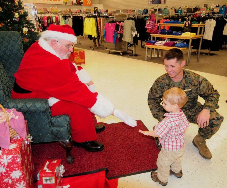 Marine Staff Sgt. Lawrence Battiste and his son Jonathan, natives of Grand Blanc, Mich., greet Santa during a visit to their local Exchange on Okinawa, Japan, Dec. 23, 2013. (photo by Staff Sgt. Robert DeDeaux, Exchange Pacific Region Public Affairs)