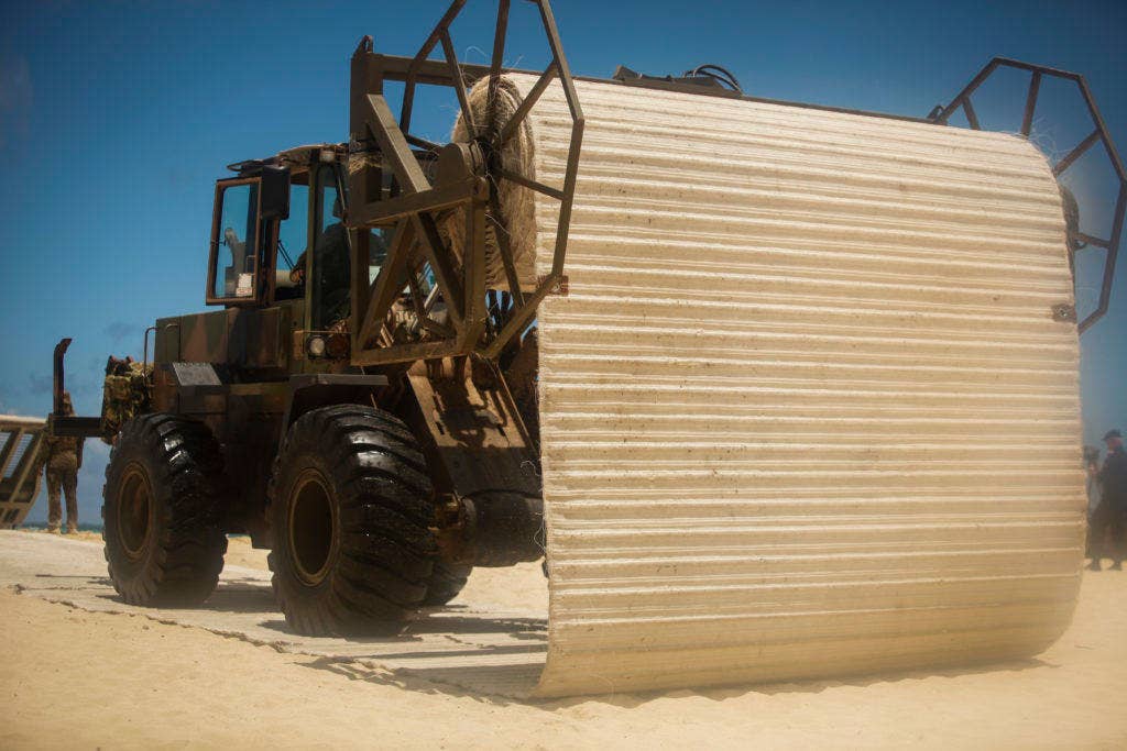 An LX-120 front end loader lays down beach matting during Rim of the Pacific 2016. The matting makes it easier for follow-on vehicles to cross the loose sand. (Photo: US Marine Corps Sgt. William L. Holdaway)