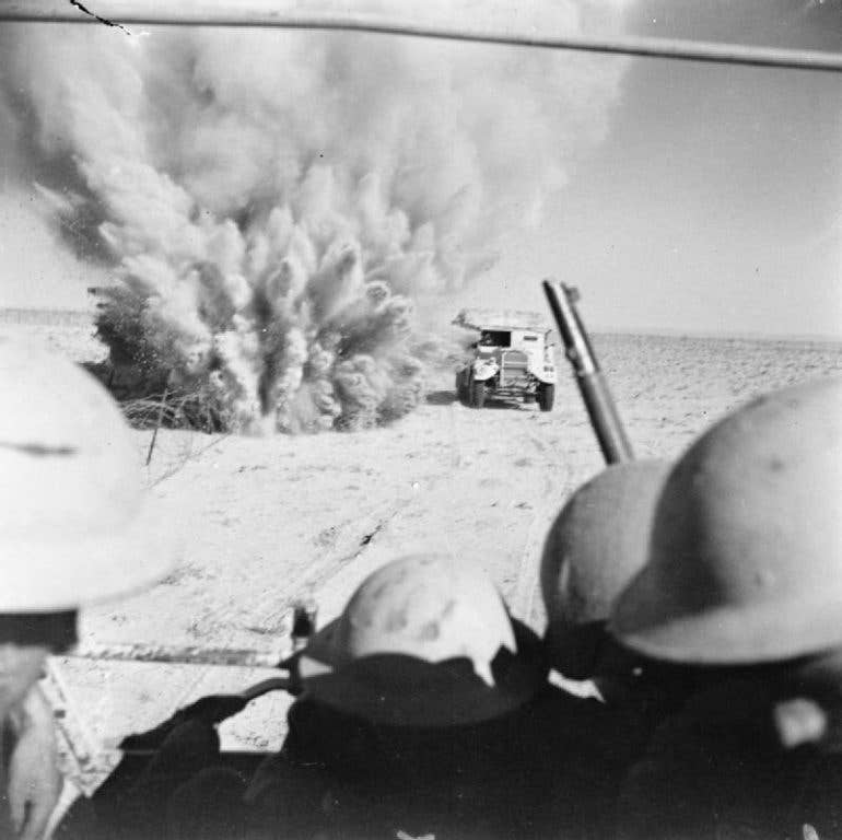 A mine explodes close to a British artillery tractor as it advances through enemy minefields and wire to the new front line at the Second Battle of El Alamein. (Imperial War Museum photo)