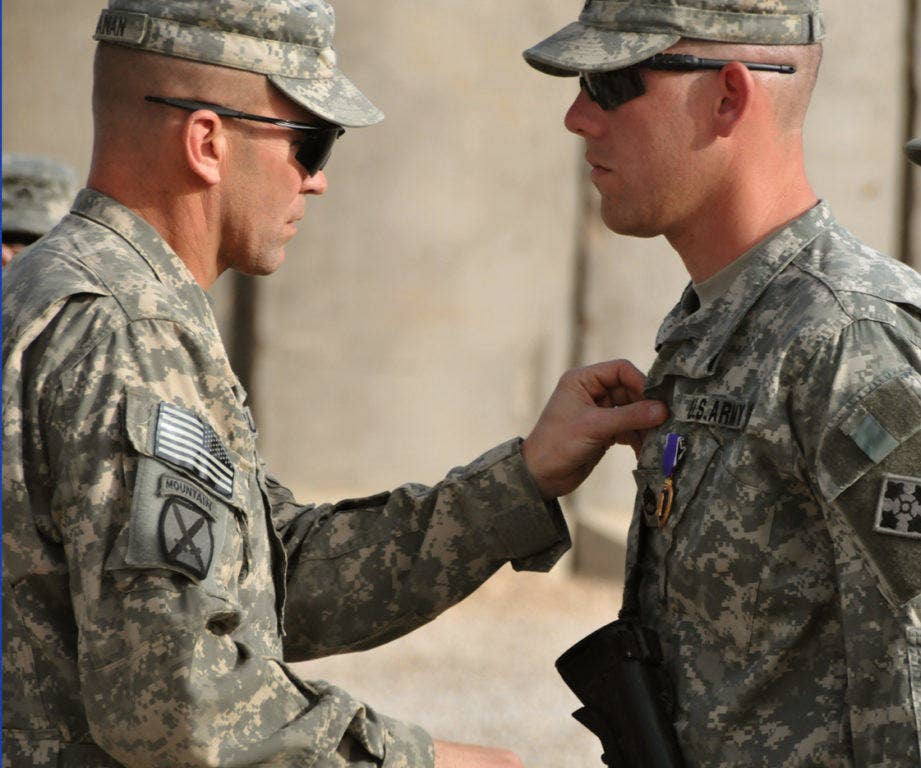 Army Brig. Gen. Jeffrey Buchanan, deputy commanding general for operations, Multi-National Division-Center, recloses the top part of Staff Sgt. Matthew Harvey's uniform after pinning a Purple Heart on him during an award ceremony March 20, 2009. (Photo: Sgt. Rodney Foliente, USA)