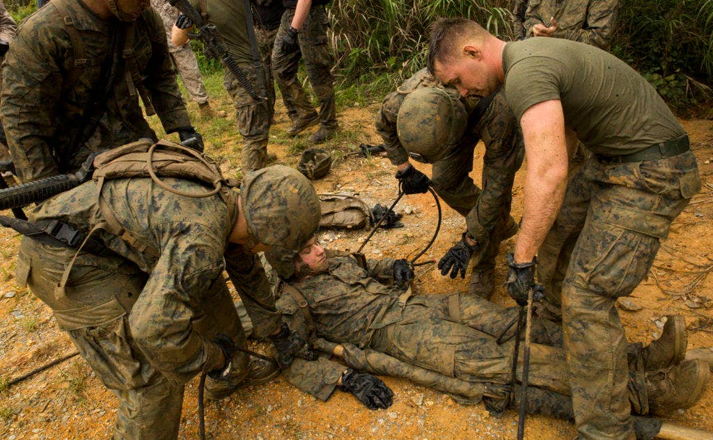 Marines and sailors prepare to carry a simulated casualty using a field-expedient stretcher during the jungle endurance course at the Jungle Warfare Training Center on Marine Corps Base Camp Smedley D. Butler. (Photo: U.S. Marine Corps Lance Cpl. Diamond N. Peden)