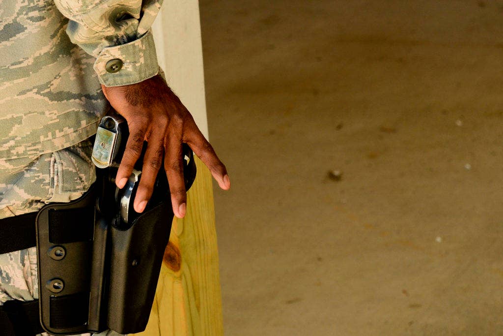 A U.S. Air Force airman holsters a 9mm pistol at the Combat Arms Training and Maintenance range at Langley Air Force Base, Va., Oct. 30, 2015. Holsters like this one require the user to manually flip a retention bar over the slide to keep the handgun from falling out or being easily grabbed by an opponent. (U.S. Air Force photo by Airman 1st Class Derek Seifert)