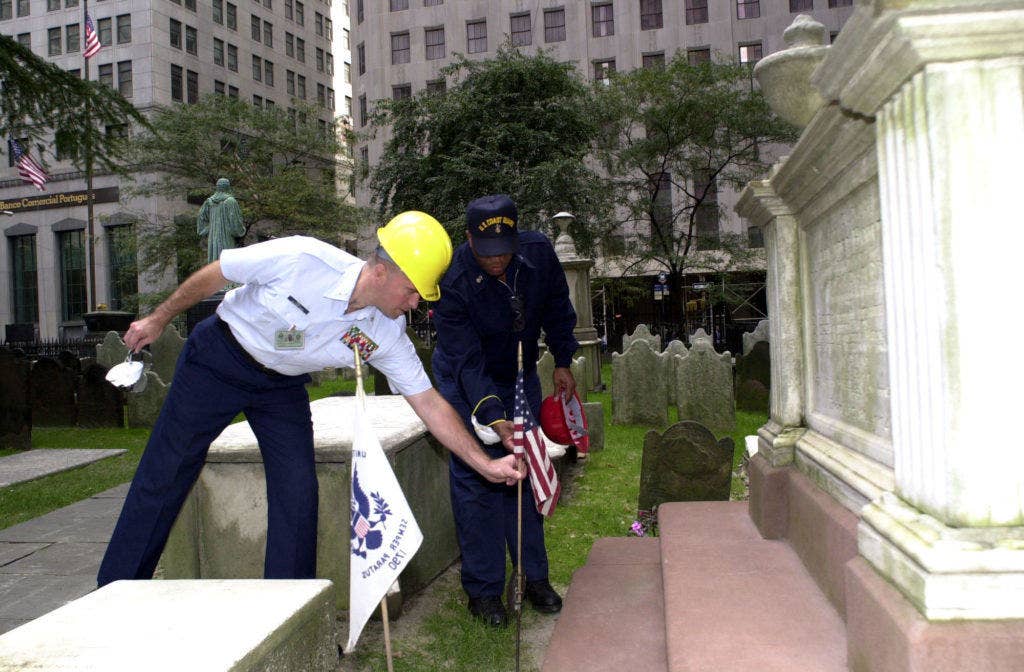 U.S. Coast Guard Senior Chief Petty Officer Steven Koll and Master Chief Petty Officer of the Coast Guard, Vince Patton, adjust the flag placed at the grave site of Alexander Hamilton, the 'father of the Coast Guard', Thursday at the cemetery of Trinity Church, a few blocks away from the WTC disaster site. (USCG photo by PA2 Mark Mackowiak)