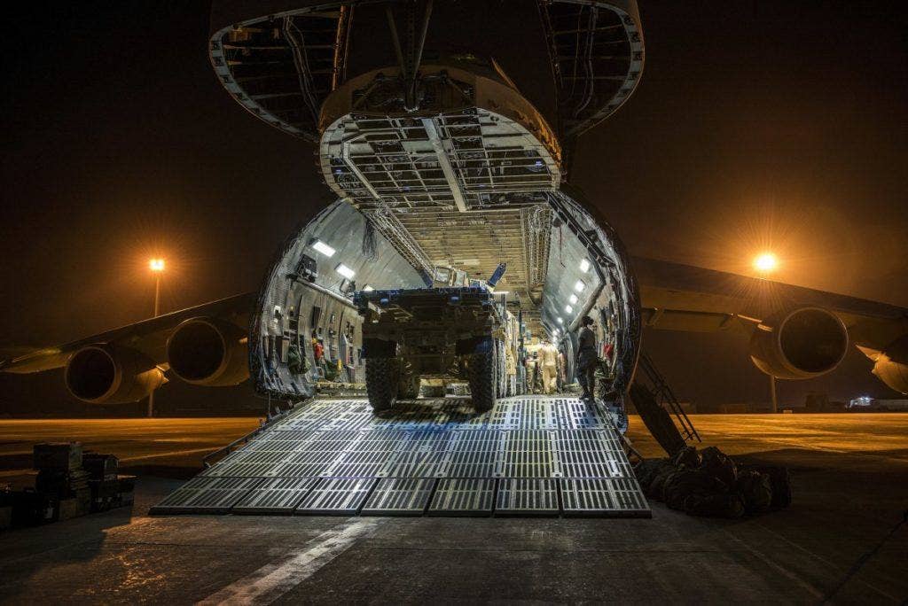 Airmen from the 9th Airlift Squadron and 455th Expeditionary Aerial Port Squadron work with Marines from the Marine Expeditionary Brigade to load vehicles into a C-5 Super Galaxy October 6, 2014, at Camp Bastion, Afghanistan. | US Air Force photo