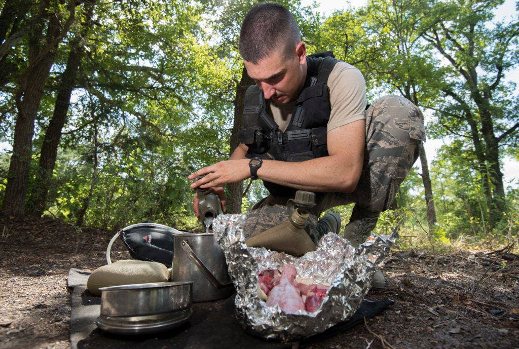A U.S. Air Force Airman Survival, Evasion, Resistance, Escape candidate adds water to a cooking pot at Camp Bullis, Texas. SERE candidates are encouraged to boil their meals to keep as much nutrition in the food as possible. (U.S. Air Force photo by Tech. Sgt. Chad Chisholm)