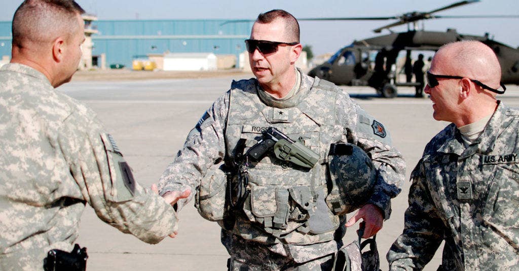 Then-Brig. Gen. John Rossi shakes hands with Command Sgt. Maj. Jim Thomson, Nov. 12, after arriving on Camp Taji, Iraq, for a visit to the troops there. On Rossi's left walks Col. Frank Muth, the commander of the Enhanced Combat Aviation Brigade, 1st Infantry Division. (Photo U.S. Army)