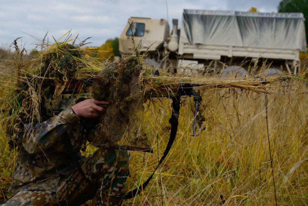A Latvian soldier checks the camouflage of his weapon before taking part in the stalking challenge of the European Best Sniper Squad Competition at the 7th Army Training Command's, Grafenwoehr Training Area, Bavaria, Germany, Oct. 26, 2016. (Photo and cutline: U.S. Army Spc. Emily Houdershieldt)