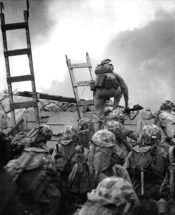 First Lieutenant Baldomero Lopez leads the 3rd Platoon, Company A, 1st Battalion, 5th Marines over the seawall on the northern side of Red Beach, as the second assault wave lands, Sept. 15, 1950, during the Inchon invasion. Wooden scaling ladders are in use to facilitate disembarkation from the LCVP that brought these men to the shore. Lt. Lopez was killed in action within a few minutes while assaulting a North Korean bunker. (Photo: U.S. National Archives)