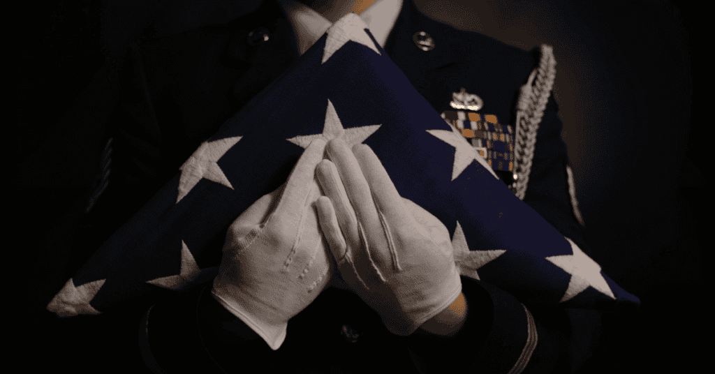 The white gloved hands of a member of the U.S. Air Force Honor Guard hold a folded United States flag. The triangular shaped folded flag and accompanying ceremony is an inspiring way to honor the flag and what it represents during solemn ceremonies. (U.S. Air National Guard Photo by Master Sgt. Vincent De Groot 185th ARW Wing PA