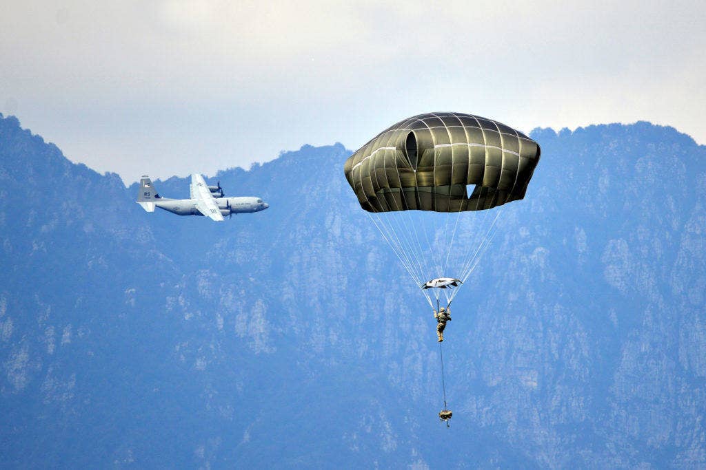 A Paratrooper from the 173rd Airborne Brigade prepares to land. In the background, a C-130 Hercules. (U.S. Army photo by Visual Information Specialist Paolo Bovo)