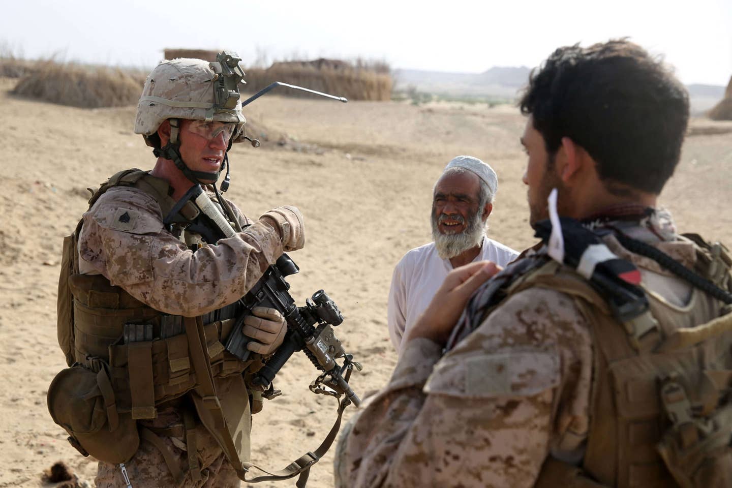 Sergeant Warren Sparks, squad leader, Bravo Company, 1st Battalion, 7th Marine Regiment, and a native of Baton Rouge, Louisiana, is assisted by an interpreter to gather intelligence from a local Afghan during a mission in Helmand province, Afghanistan, May 1, 2014. (U.S. military photo)