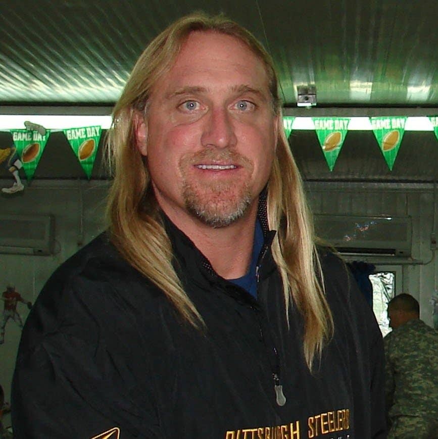 Former NFL linebacker Kevin Greene is greeted by Senior Master Sgt. Damian Orslene, 506th Air Expeditionary Group Personnel In Support of Contingency Operations superintendent, in the dining facility Feb. 2. Mr. Greene is traveling to military bases in Iraq to show support and increase the morale for U.S. service members. Throughout his career, he played for the Las Angeles Rams, Pittsburgh Steelers and Carolina Panthers. (USAF Photo)