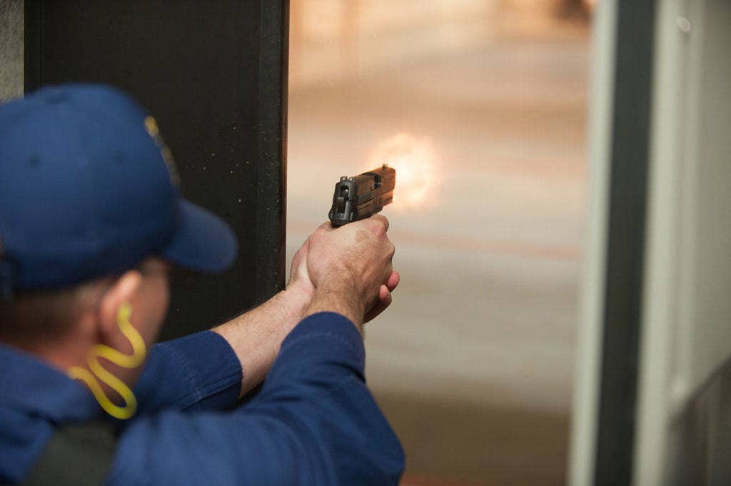 A Coast Guard member is seen firing a Sig Sauer P229R DAK pistol at an indoor range located on Joint Base Cape Cod, Tuesday, Nov. 24, 2015. (U.S. Coast Guard photo by Petty Officer 3rd Class Andrew Barresi)