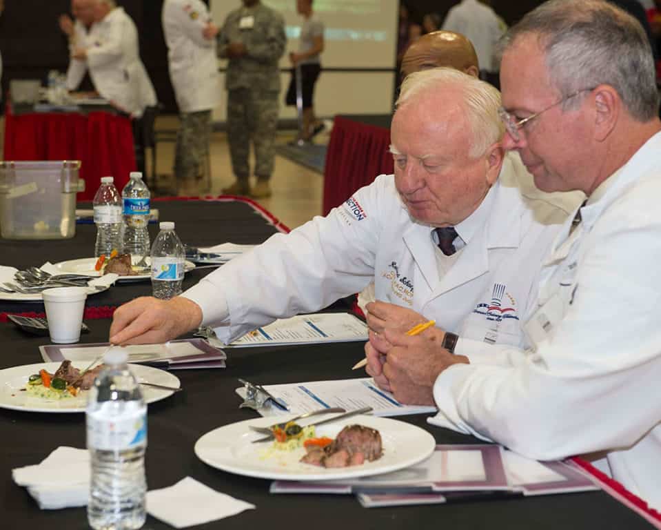 A pair of master chefs from the American Culinary Federation judge a meal at the 41st Annual Military Culinary Arts Competitive Training Event (MCACTE). The MCACTE is the largest culinary competition in North America, and has been held since 1973. (U.S. Navy photo by Mass Communication Specialist 2nd Class Nathan McDonald/Released).
