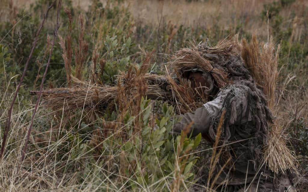 Corporal Brighten Bell, a student undergoing the 2nd Marine Division Combat Skills Center's Pre-Scout Sniper Course, acquires a target during a stalking exercise at Camp Lejeune, N.C., Jan. 22, 2016. The exercise required students to traverse approximately 1,000 meters of high grass and fire on a target, all without being detected. (U.S. Marine Corps photo by Cpl. Paul S. Martinez/Released)