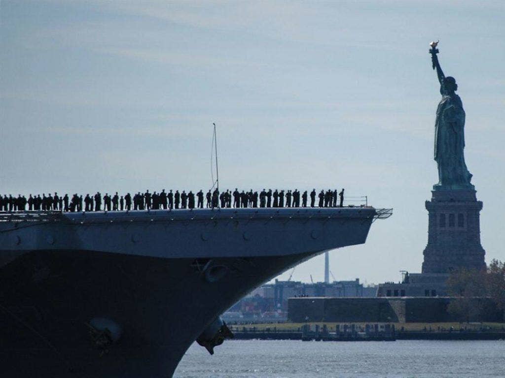The amphibious assault ship USS Iwo Jima sails past the Statue of Liberty as it enters New York Harbor, November 10, 2016, before Veterans Week NYC 2016, which honors the service of all US veterans. About 1,000 sailors and more than 100 Marines from the ship planned to participate in events throughout the city, including the Veterans Day parade. | US Navy photo by Petty Officer 2nd Class Carla Giglio
