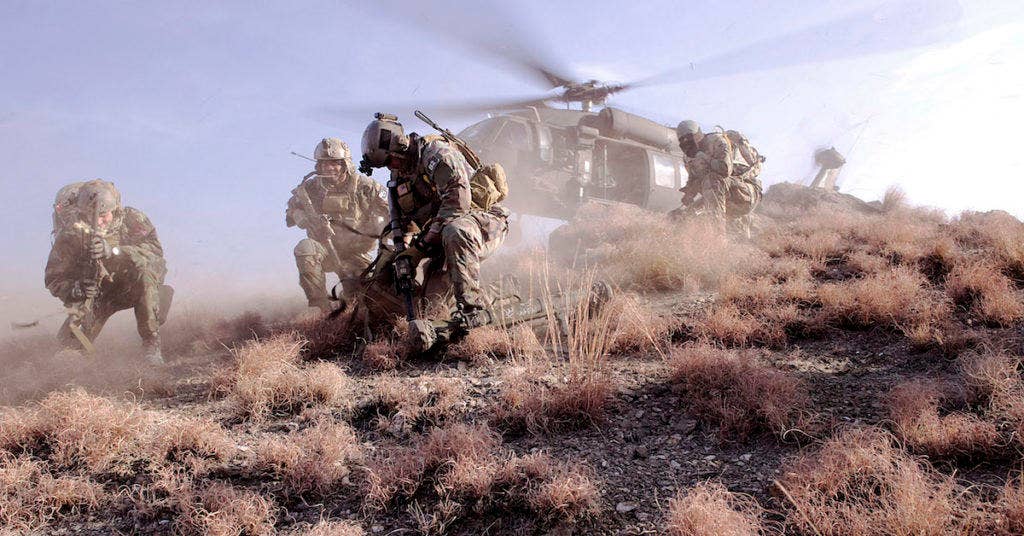 U.S. Special Operations personnel take cover to avoid flying debris as they prepare to board a UH-60 Black Hawk helicopter during a mission in Kunar province, Afghanistan, on Feb. 25, 2012. (Dept. of Defense photo by Petty Officer 2nd Class Clayton Weiss, U.S. Navy)
