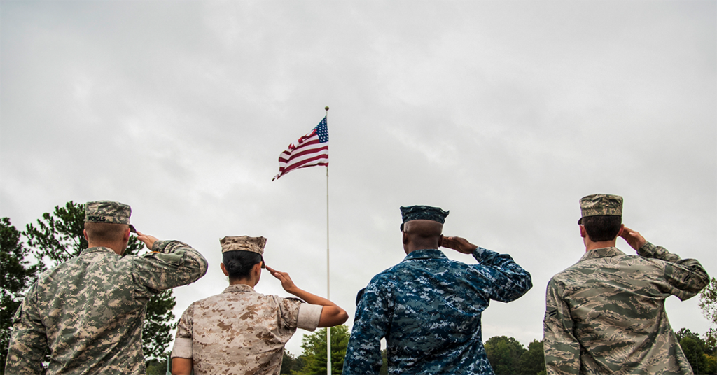 Service members saluting the raised American flag. (Photo: Airman 1st Class Harry Brexel)