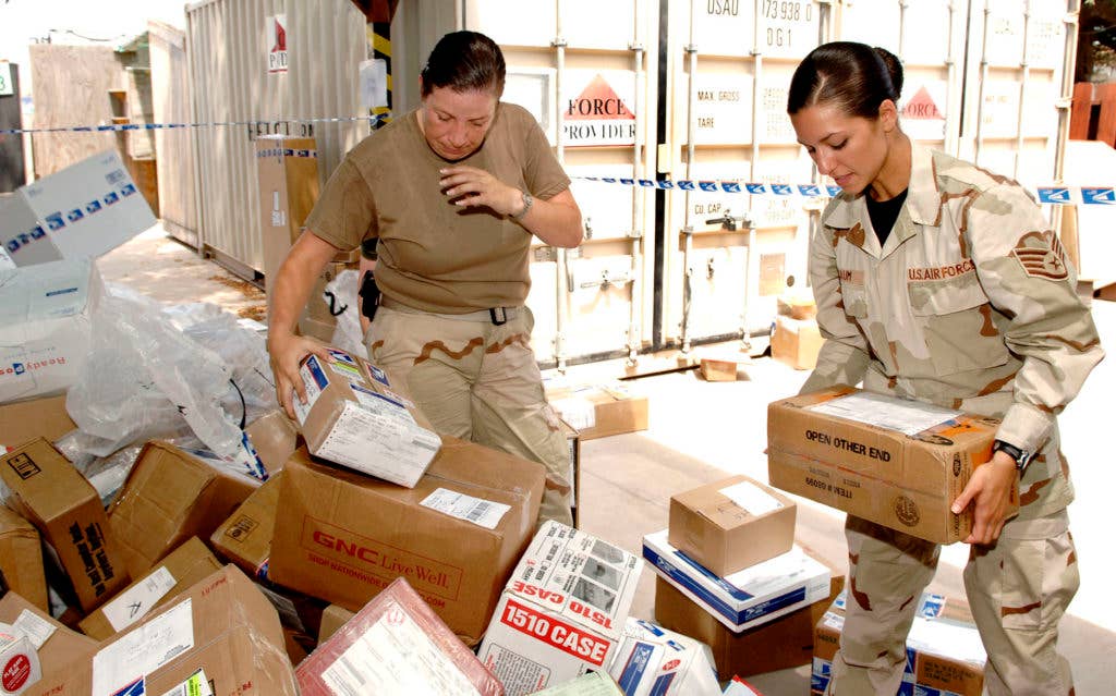 Air Force Staff Sgt. Beatriz Baum works alongside Navy Petty Officer 3rd Class Misty Parker during a scramble to unload more than 5,000 lbs. of mail slated for delivery to service members deployed to Joint Task Force Horn of Africa at the postal center at Camp Lemonier in Djibouti. (U.S. Air Force photo/Daren Reehl)
