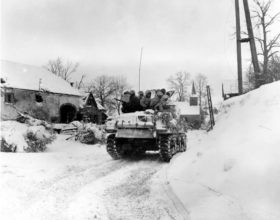 Soldiers with the 1st Division, U.S. First Army, ride on a tank, during their advance on the town of Schopen, Belgium. (Photo: U.S. Army Sgt. Bill Augustine)