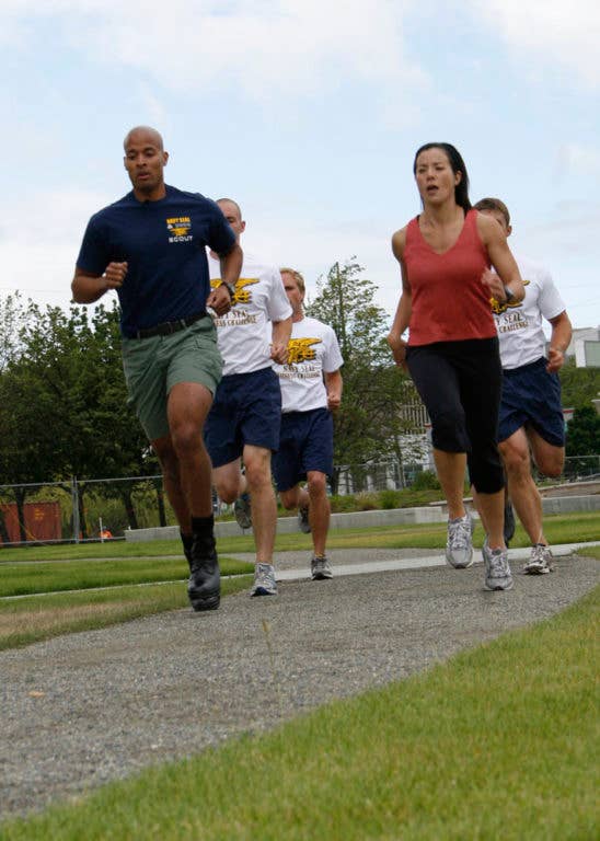 Navy SEAL David Goggins runs with a news reporter during a press event. (Photo: U.S. Navy Petty Officer 2nd Class Michelle Kapica)