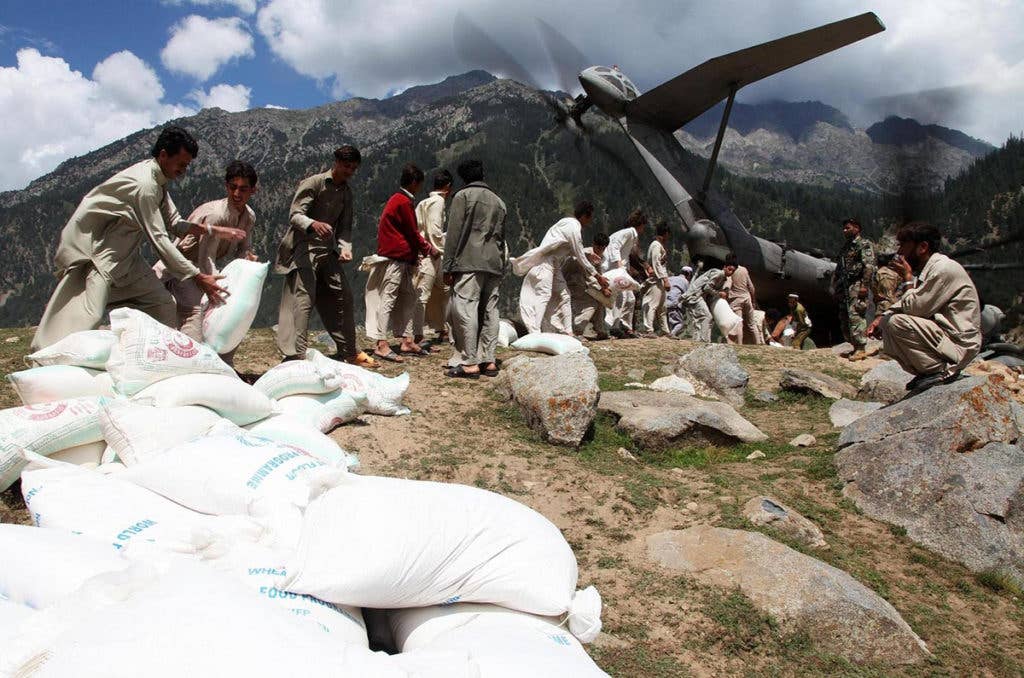 Local men assist U.S. Marines in offloading hundreds of bags of flour aboard a KC-130J Super Hercules aircraft at Gilgit Air Base, Pakistan, Sept. 8, 2010. (Photo: U.S. Air Force Staff Sgt. Andy M. Kin)